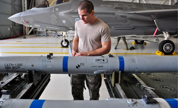 Un aviateur sécurise un missile air-air avancé AIM-120 à moyenne portée, avant de le charger à bord d'un F-35A Lightning II.